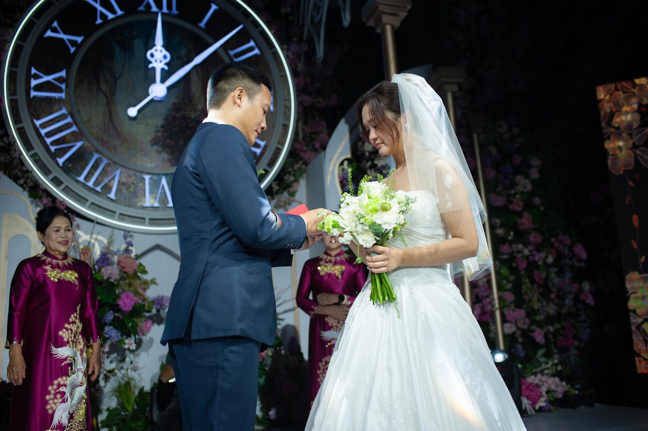 Crafting Captivating Headlines: Your awesome post title goes here Bride and groom exchange vows in a beautiful indoor wedding ceremony with floral decor and a classic clock backdrop.